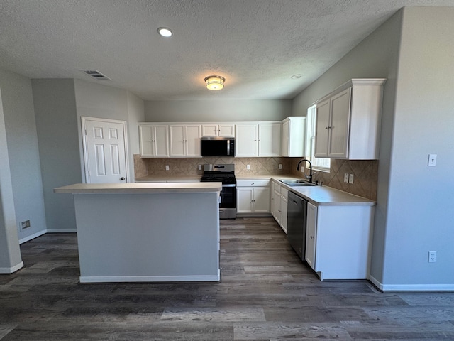 kitchen featuring a center island, sink, appliances with stainless steel finishes, dark hardwood / wood-style flooring, and white cabinetry