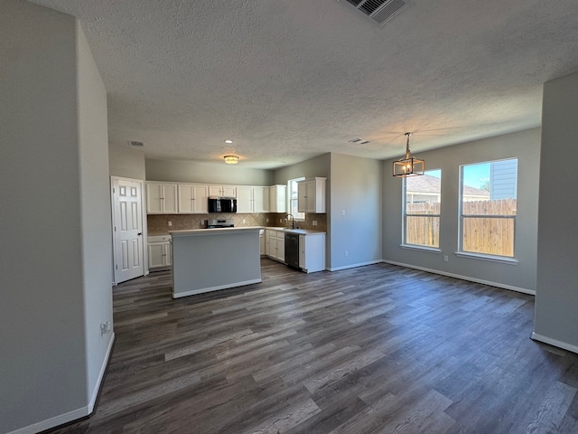 kitchen featuring appliances with stainless steel finishes, decorative light fixtures, white cabinets, a center island, and dark hardwood / wood-style floors