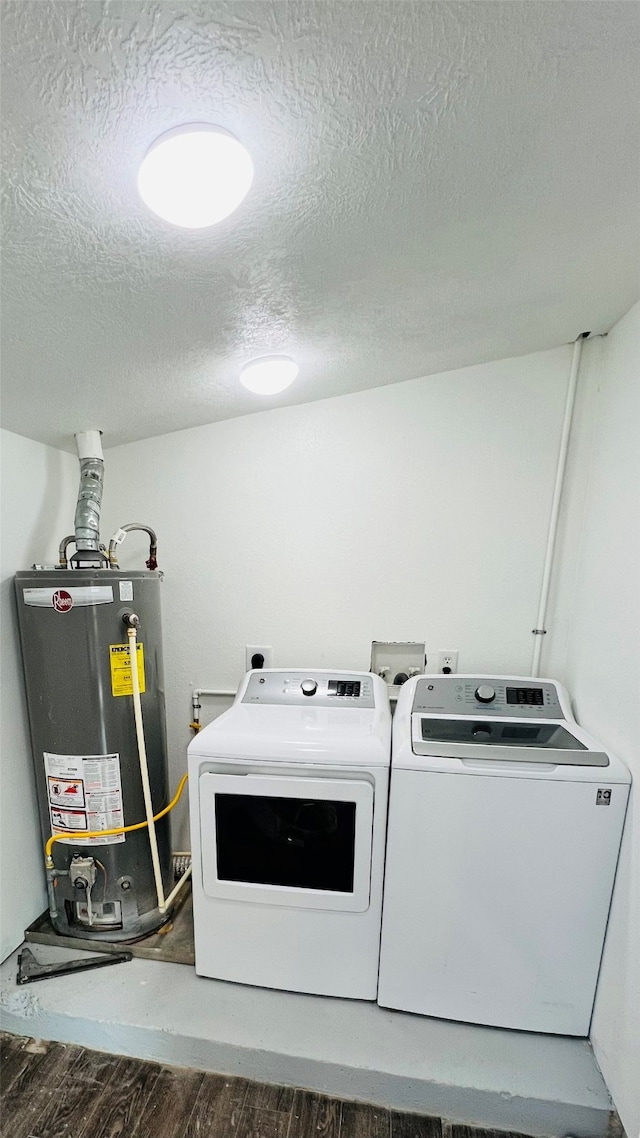 laundry room featuring washer and dryer, a textured ceiling, dark wood-type flooring, and water heater