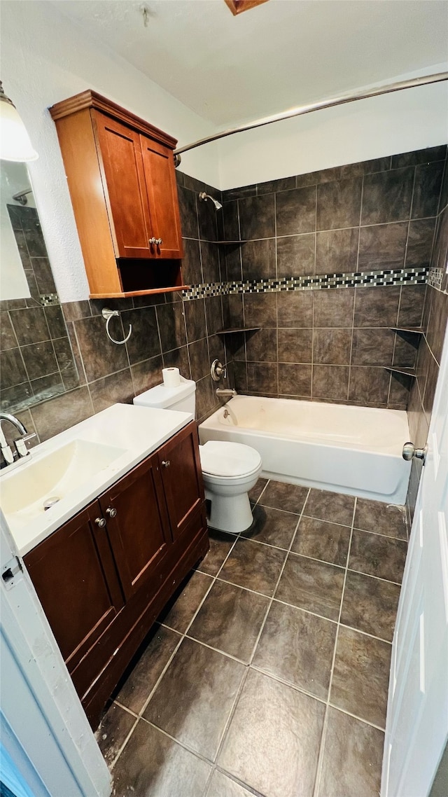 full bathroom featuring vanity, backsplash, tile patterned flooring, tiled shower / bath combo, and toilet