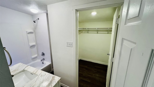 bathroom with hardwood / wood-style floors, vanity, a textured ceiling, and bathtub / shower combination