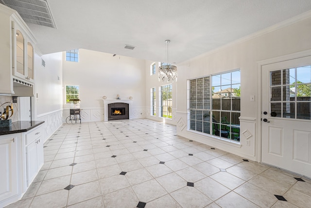 unfurnished living room featuring crown molding, light tile patterned floors, and a chandelier