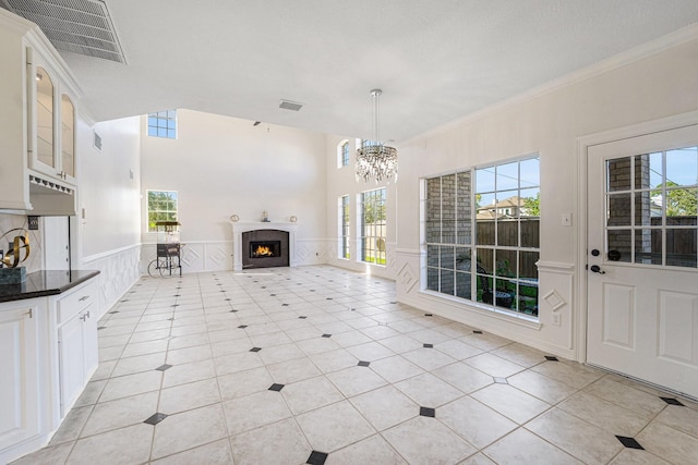 8215 Arrowhead Ln, Houston, TX 77075 - unfurnished living room featuring a warm lit fireplace, ornamental molding, a chandelier, light tile patterned floors, and wainscoting