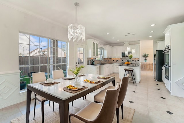 dining room featuring sink, an inviting chandelier, crown molding, and light tile patterned flooring