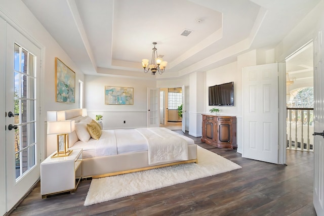 bedroom with dark hardwood / wood-style flooring, a raised ceiling, and a notable chandelier