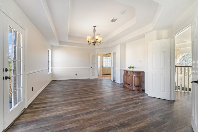 unfurnished dining area featuring a chandelier, dark hardwood / wood-style flooring, and a tray ceiling