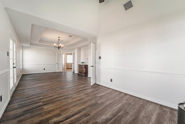 unfurnished living room with dark wood-type flooring, a tray ceiling, and french doors