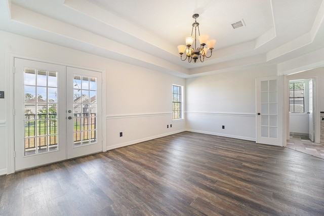 empty room featuring a raised ceiling, french doors, and dark wood-type flooring