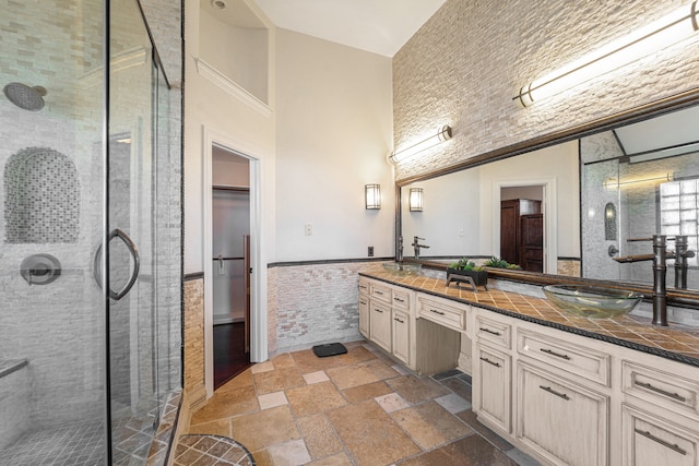 bathroom with vanity, a shower with shower door, tile walls, and a high ceiling