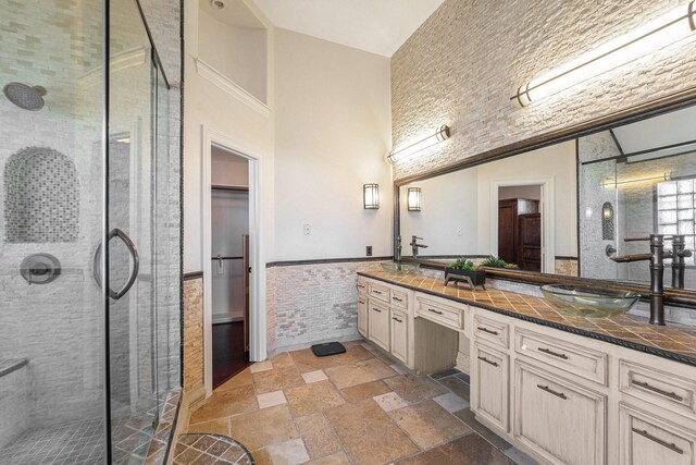 8215 Arrowhead Ln, Houston, TX 77075 - bathroom featuring a stall shower, double vanity, tile walls, wainscoting, and stone tile floors