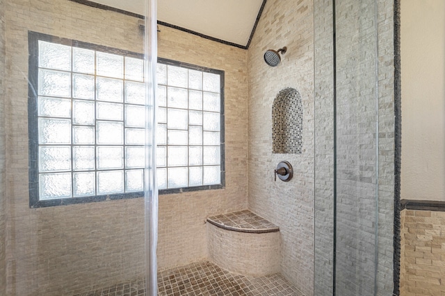 bathroom featuring a tile shower, tile walls, and vaulted ceiling