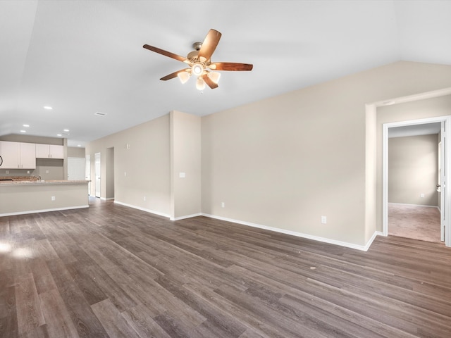 unfurnished living room with ceiling fan, dark wood-type flooring, and vaulted ceiling