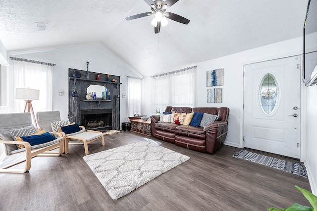 living room with a textured ceiling, dark hardwood / wood-style flooring, vaulted ceiling, and ceiling fan