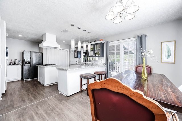 kitchen featuring hardwood / wood-style floors, custom exhaust hood, a textured ceiling, and black refrigerator with ice dispenser