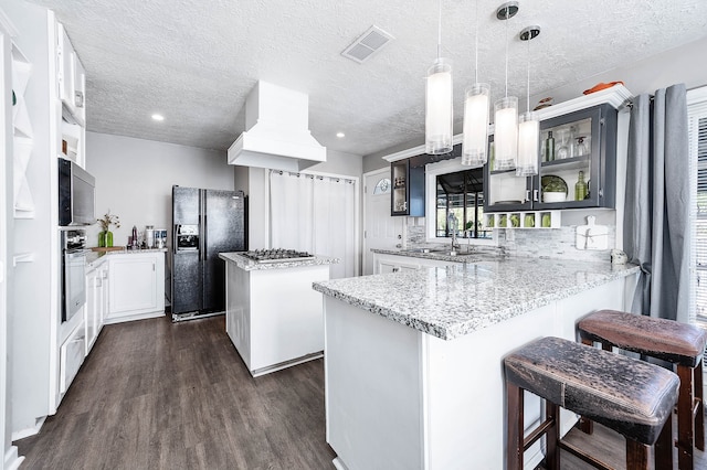 kitchen featuring a center island, dark wood-type flooring, stainless steel appliances, pendant lighting, and custom range hood