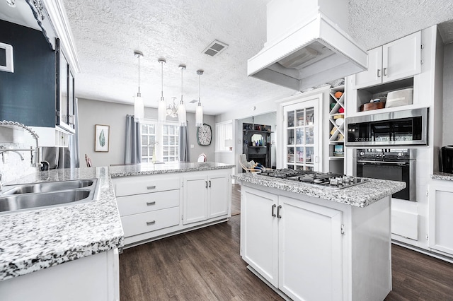 kitchen featuring a textured ceiling, dark wood-type flooring, white cabinets, a center island, and hanging light fixtures