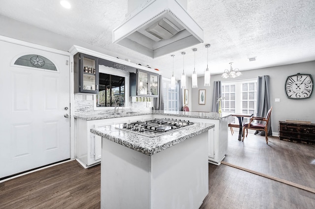 kitchen with a textured ceiling, a center island, and stainless steel gas stovetop