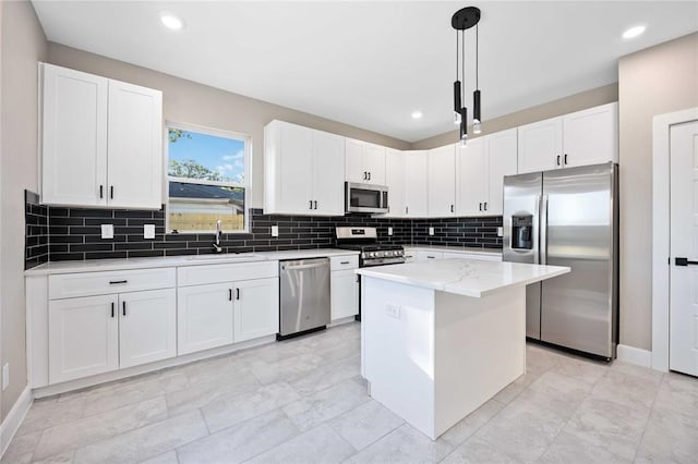 kitchen featuring pendant lighting, light stone countertops, a kitchen island, white cabinetry, and stainless steel appliances