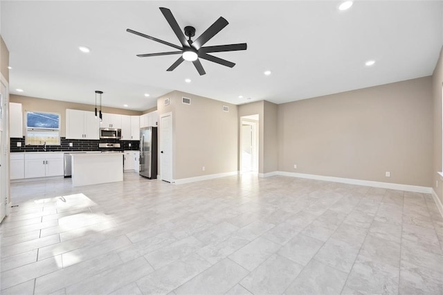 unfurnished living room with ceiling fan and sink