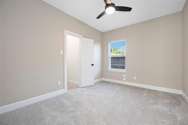 spare room featuring ceiling fan, light carpet, and vaulted ceiling