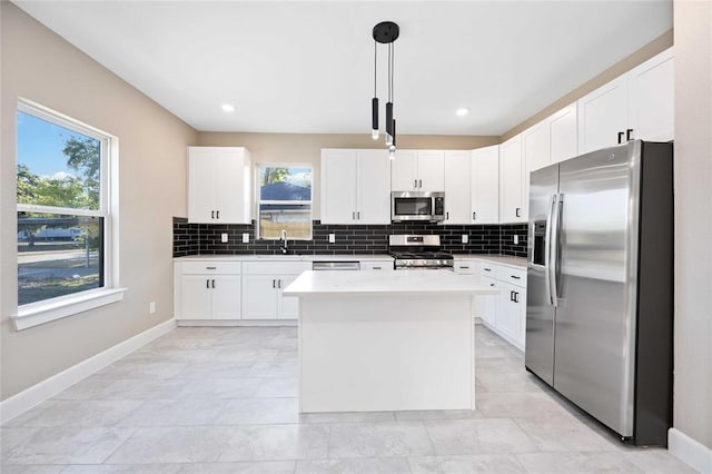 kitchen with a wealth of natural light, a kitchen island, stainless steel appliances, and hanging light fixtures