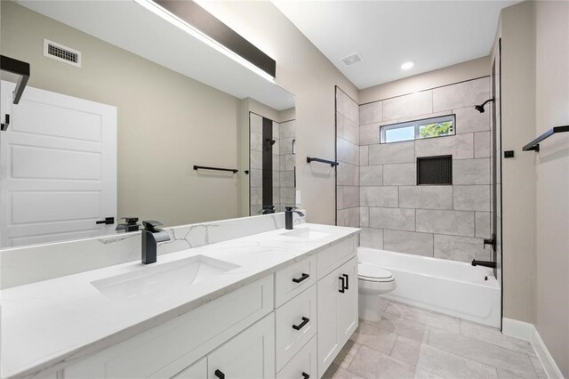 full bathroom featuring vanity, tiled shower / bath combo, and toilet