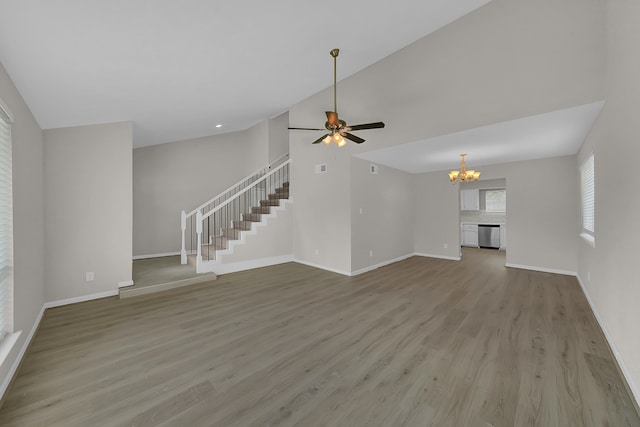 unfurnished living room featuring vaulted ceiling, ceiling fan with notable chandelier, and light hardwood / wood-style floors