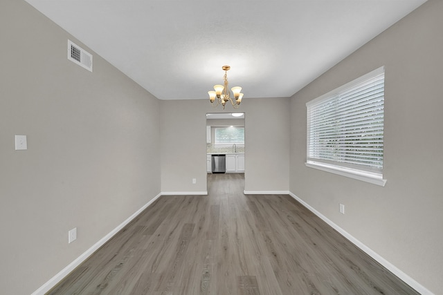 unfurnished dining area featuring a chandelier and light hardwood / wood-style floors