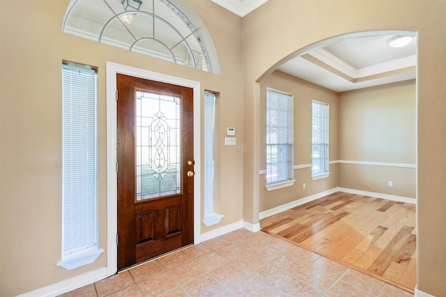 foyer entrance featuring crown molding and light hardwood / wood-style flooring