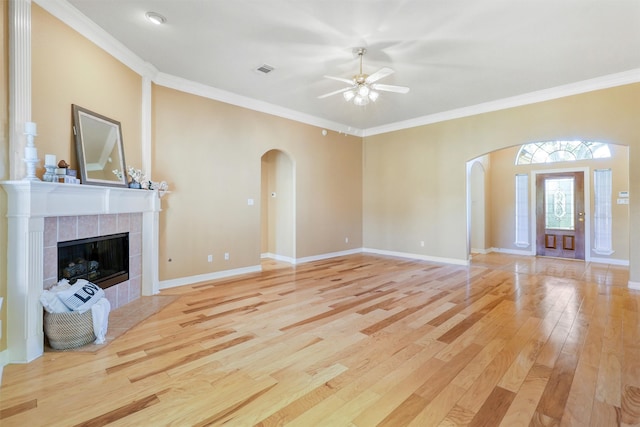 unfurnished living room featuring ceiling fan, light wood-type flooring, ornamental molding, and a tiled fireplace