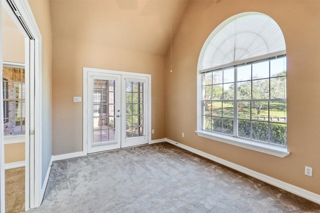 unfurnished room featuring french doors, carpet, a healthy amount of sunlight, and high vaulted ceiling