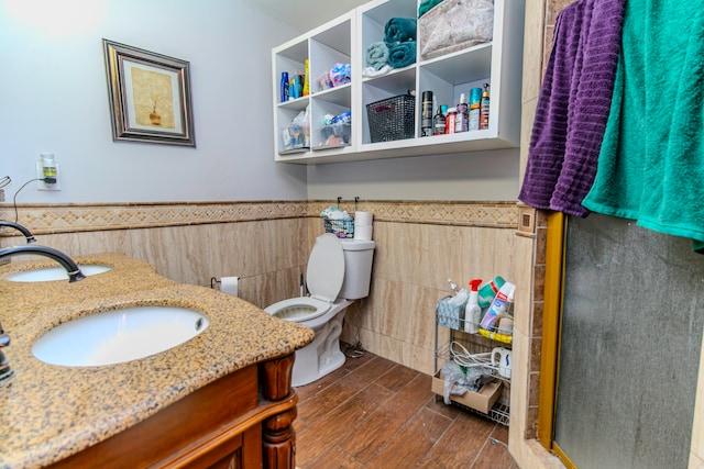 bathroom featuring vanity, hardwood / wood-style flooring, toilet, tile walls, and a shower with shower door