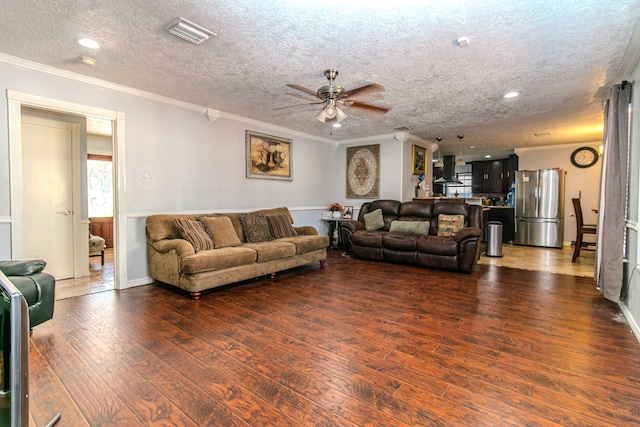 living room with a textured ceiling, dark hardwood / wood-style floors, ceiling fan, and ornamental molding