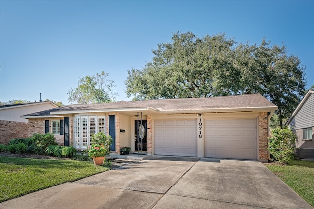 ranch-style home with a garage, a front lawn, and central AC unit