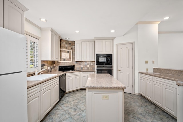 kitchen with backsplash, a kitchen island, black appliances, white cabinets, and sink