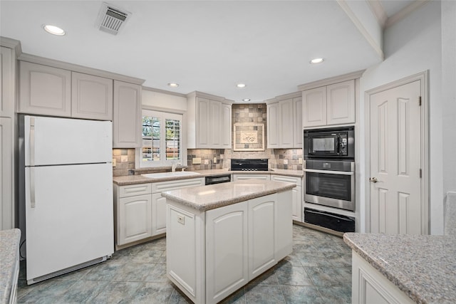 kitchen featuring a kitchen island, black appliances, decorative backsplash, sink, and light stone countertops