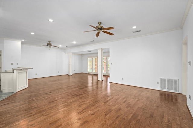 unfurnished living room with decorative columns, hardwood / wood-style floors, crown molding, and ceiling fan