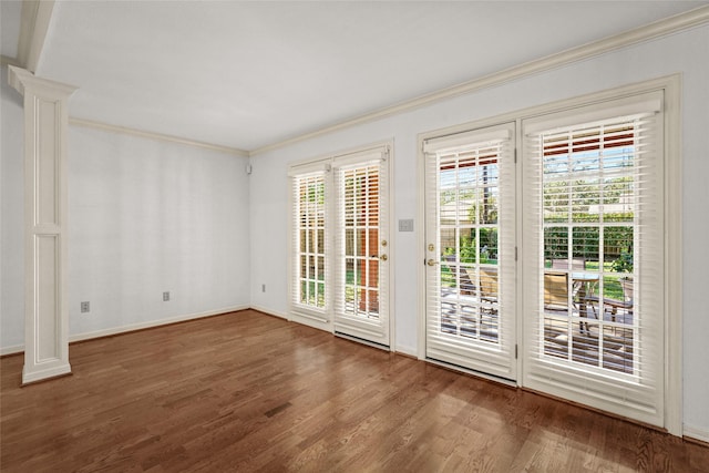 doorway with hardwood / wood-style flooring, crown molding, and ornate columns