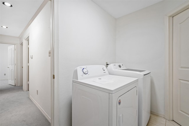 laundry area with washing machine and dryer, ornamental molding, and light carpet