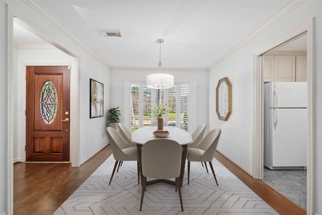 dining area with dark wood-type flooring and crown molding