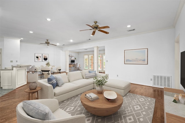 living room with ornate columns, ornamental molding, light hardwood / wood-style flooring, and ceiling fan