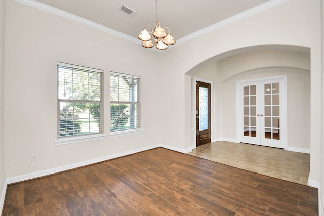 empty room with ornamental molding, a chandelier, french doors, and hardwood / wood-style floors