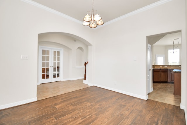 unfurnished room featuring a chandelier, dark wood-type flooring, french doors, and ornamental molding