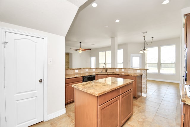 kitchen with dishwasher, light stone counters, decorative light fixtures, a kitchen island, and sink