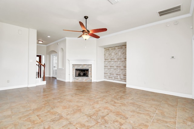 unfurnished living room with ceiling fan, a stone fireplace, and crown molding