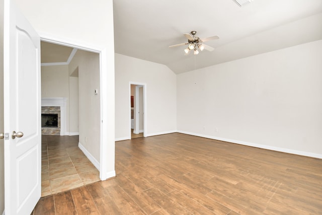 unfurnished room featuring a stone fireplace, hardwood / wood-style flooring, vaulted ceiling, and ceiling fan