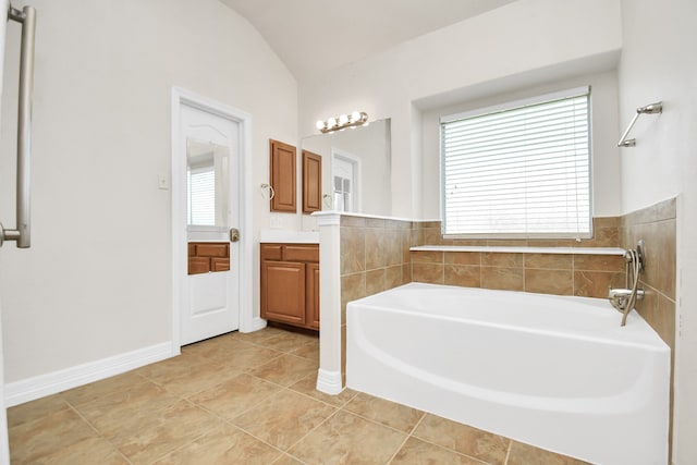 bathroom featuring tile patterned floors, vanity, a bath, and lofted ceiling