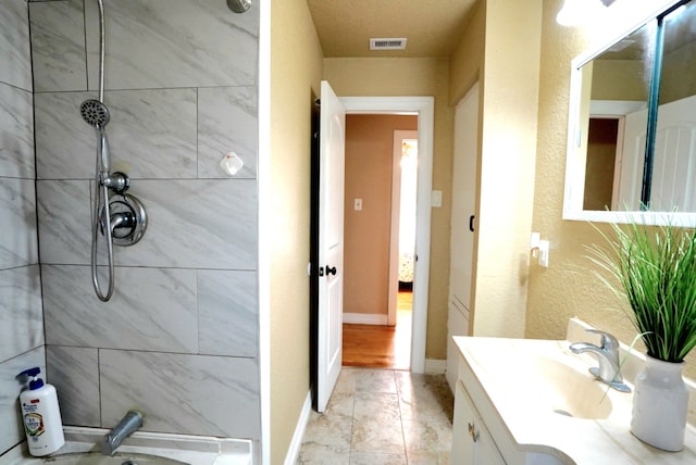 bathroom with vanity and a tile shower