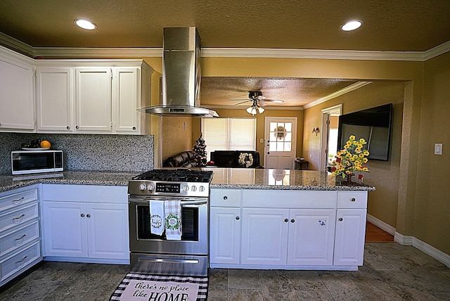 kitchen featuring appliances with stainless steel finishes, ornamental molding, island range hood, ceiling fan, and white cabinetry