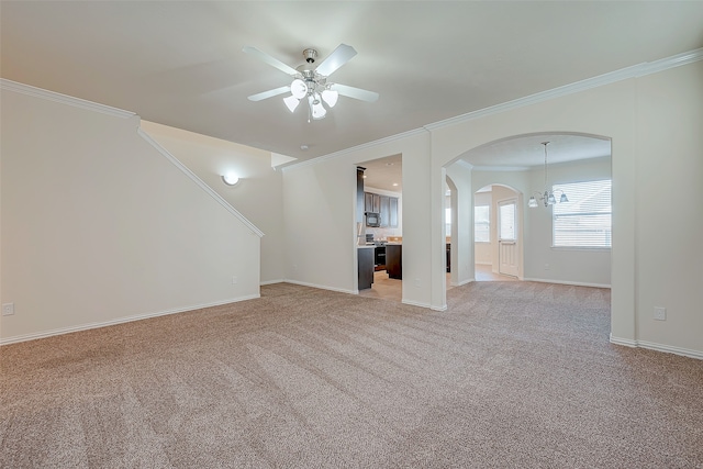 unfurnished living room featuring ceiling fan with notable chandelier, light colored carpet, and crown molding